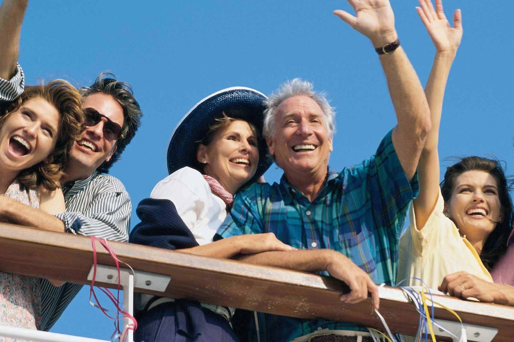 Group of people waving from the rail of a group cruise booked by a travel agent specializing in group cruising.